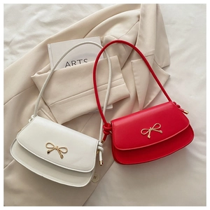 Detailed shot of leather shoulder bag with golden bow hardware and side knot design