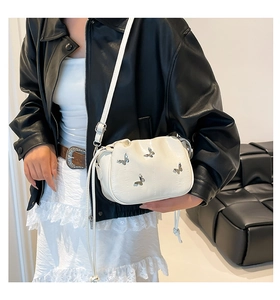 Detail of white cloud bag featuring silver butterfly accents and drawstring fold design