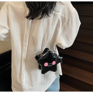 Detail of star-shaped black crossbody bag with smiley face and silver chain strap