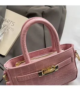 Close-up of pink crocodile texture handbag with round handle and gold hardware
