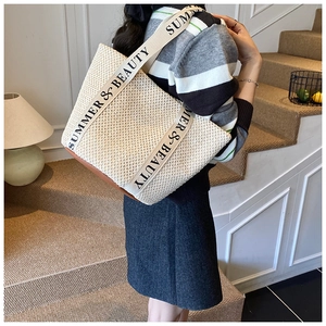 Détail du sac cabas en paille tissée avec bandoulière en toile et base marron