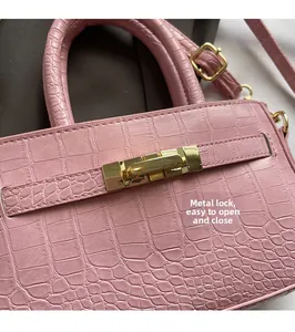Detail of pink faux crocodile leather handbag with golden hardware rotating lock closure