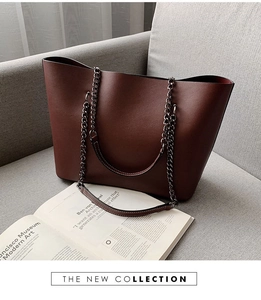 Chic burgundy tote bag with chain strap and red lining shown on a grey fabric sofa