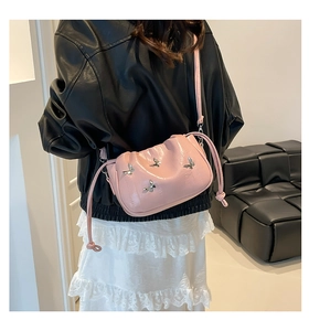 Detail of pink pleated crossbody bag featuring silver butterfly charms and knotted drawstrings