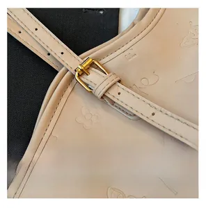 Macro detail of beige embossed leather bag featuring gold buckle and floral texture