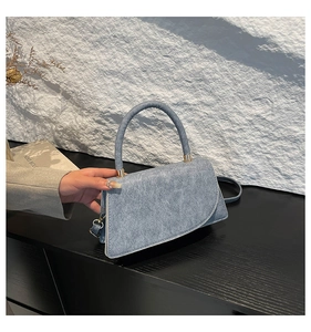 Detail of light blue denim texture handbag with gold metal clasp and single handle
