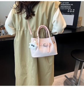 Pink pleated bucket bag detail with metal lock and a cute white plush pompom charm