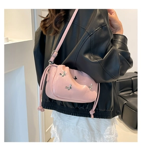 Detailed close-up of pink drawstring bag with silver butterfly studs and leather texture