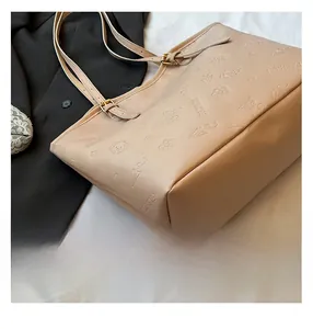Detail of embossed butterfly and floral patterns on cream faux leather tote bag surface