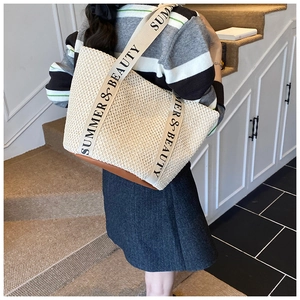 Detail of woven tote bag with canvas strap featuring Summer & Beauty lettering