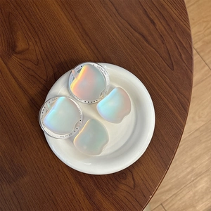 Holographic apple-shaped phone grips with pearl luster on a premium wooden background