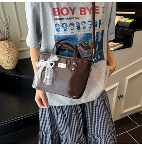 Detail of dark brown glossy bucket bag with lace bow and pearl handle decoration