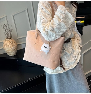 Detail of pink embossed tote bag with floral patterns and a cute white furry charm