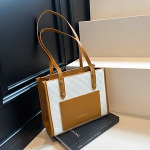 Brown and white checkered leather tote bag with shoulder strap on book