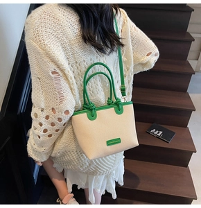 Détail du sac seau tissé beige avec bordure en cuir vert et étiquette tendance