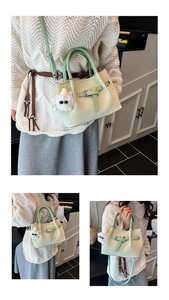 Detail of light green woven tote bag with a fuzzy monster charm and metal buckle