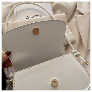 Detailed macro view of the cream leather bag with golden magnetic snap closure