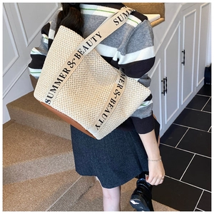 Detail of woven straw tote bag with brown leather base and Summer & Beauty canvas strap
