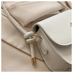 Detail of white leather handbag showing strap knot design and golden hardware accents