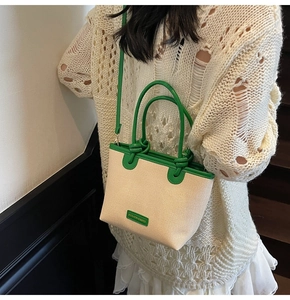 Détail du sac cabas en paille tressée avec poignées et bandoulière en cuir vert vif