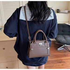 Detail einer dunkelbraunen Litschi-Muster Tasche mit Silberschnalle an einem Model