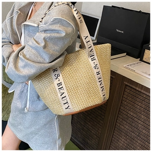 Détail du sac seau en paille avec bandoulière en toile et base en cuir marron