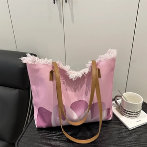 Bolso tote de lona rosa con estampado floral violeta y asas de cuero en mesa artística
