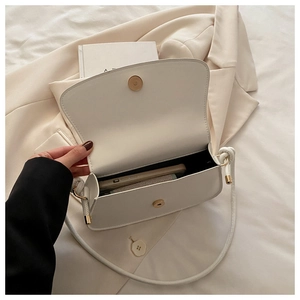 Detail view of the cream white crossbody bag showing internal space and magnetic buckle