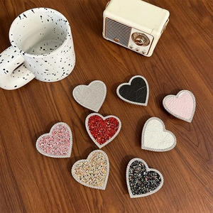 Detail of heart-shaped phone grips with rhinestones in glitter and leather textures