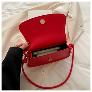 Detail view of red bow crossbody bag showing inner storage space and magnetic buckle