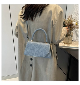 Light blue crossbody bag with textured leather and gold hardware in a modern setting