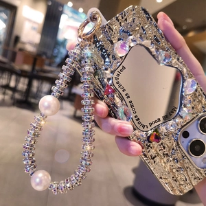 Detail of luxury pearl chain and rhinestone wavy metal phone case with heart mirror