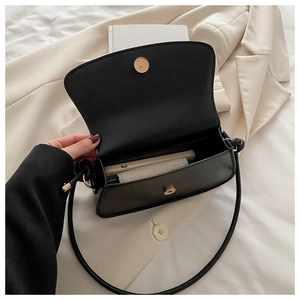 Detail view of the open black minimalist saddle bag showing interior space and magnetic clasp