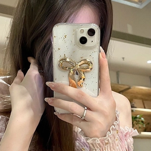 Detailed close-up of clear iPhone case with gold foil and 3D metal bow decoration