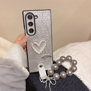 Detail of silver wrinkled phone case with pearl heart and matching pearl hand strap