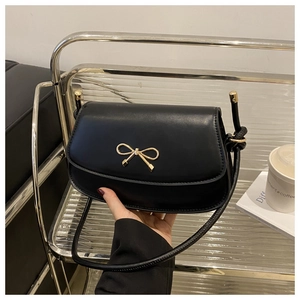 Close-up of black leather saddle bag featuring a stylish gold bow metal buckle detail