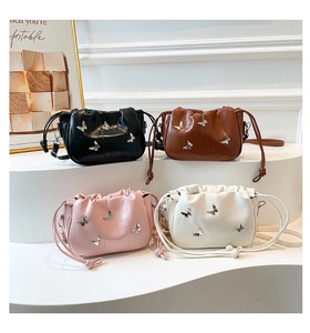 Detail view of mini bucket bags in black, brown, pink and white with silver butterfly accents