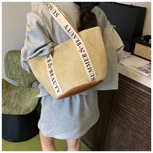 Detail of woven straw tote bag with Summer & Beauty straps and brown leather base