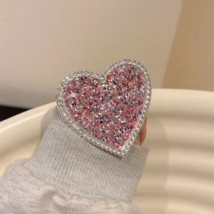Close-up of heart-shaped phone grip with pink glitter and sparkling rhinestones