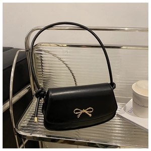 Close-up of a black leather handbag featuring a stylish golden bow-shaped metal buckle