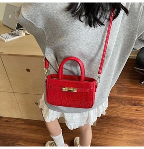 Detail of red crocodile pattern handbag with classic metal clasp and elegant stitching