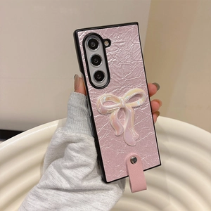 Detail of pink crinkled leather Samsung case with a 3D pearlescent bow and hand strap