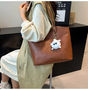 Brown large capacity tote bag featuring embossed floral patterns and plush charm on model