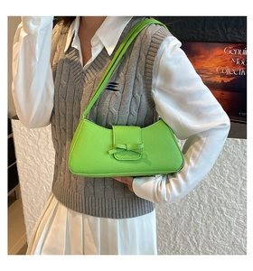 Detalle de bolso baguette verde brillante con lazo y textura de cuero lichi