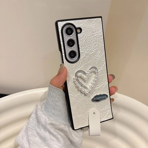 Detail of faux pearl heart design and rhinestone trim on premium pleated leather phone case
