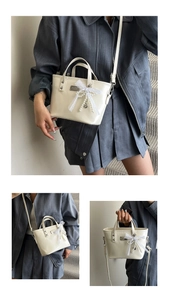 Detail of cream bucket bag with lace bow, pearl charm, and polished metal hardware