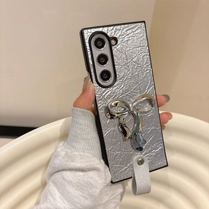 Silver wrinkled leather phone case with metallic bow and wrist strap detail view