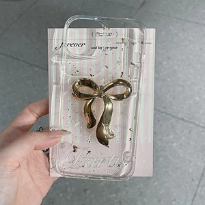 Detailed close-up of a clear iPhone case featuring a 3D gold bow and shiny gold foil accents