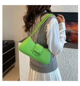 Detail of lime green baguette bag with bow and lychee texture on model's shoulder