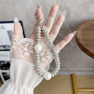 Detail of luxury pearl and rhinestone phone strap held by model wearing lace gloves